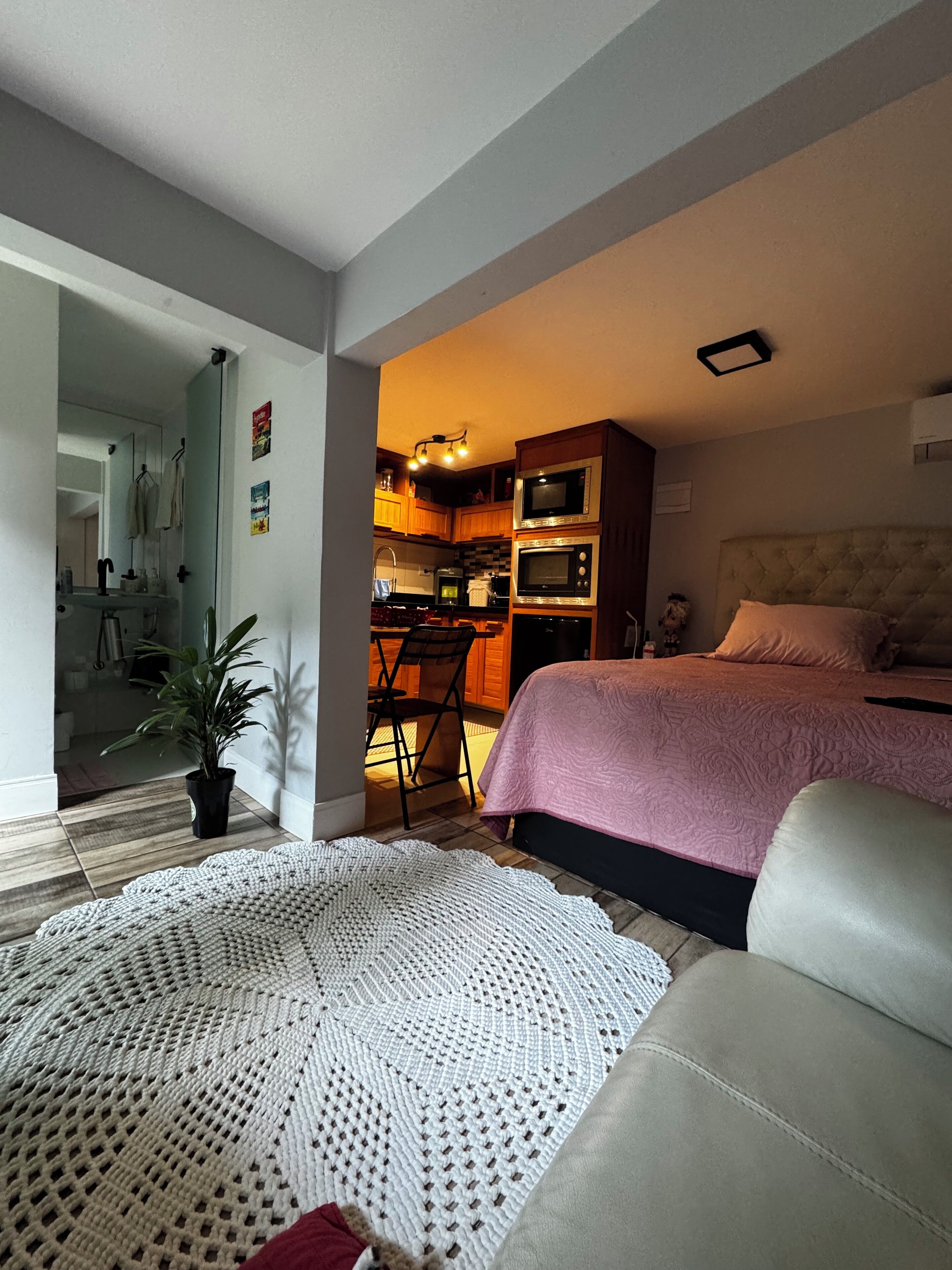 Una camera compatta con un letto, un angolo cottura e un bagno parzialmente visibile da una porta aperta.