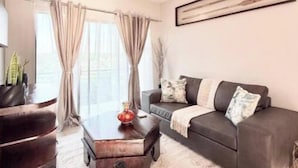 Ein modernes Wohnzimmer mit einem dunkelbraunen Sofa, einem Holztisch und einem gemusterten Teppich.