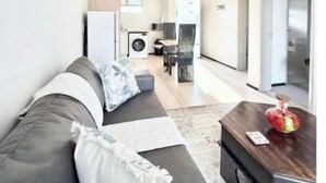Ein modernes Wohnzimmer mit einer Couch, einem Couchtisch und einem Essbereich im Hintergrund.
