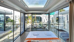 A modern hotel room with a large bed, a skylight, and a view of the surrounding area. - Sunny Pavilion (Thoddoo)