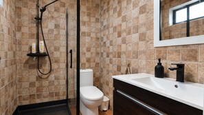 Une salle de bain avec douche, toilettes et lavabo.