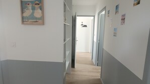 A hallway with a wooden floor, white walls, and a door at the end. - New house Porte de Noirmoutier (Beauvoir-sur-Mer)
