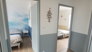 A room with a bed, a small table, and a wall with a decorative sign. - New house Porte de Noirmoutier (Beauvoir-sur-Mer)