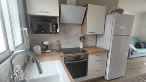 A modern kitchen with a white sink, stainless steel appliances, and wooden countertops. - New house Porte de Noirmoutier (Beauvoir-sur-Mer)
