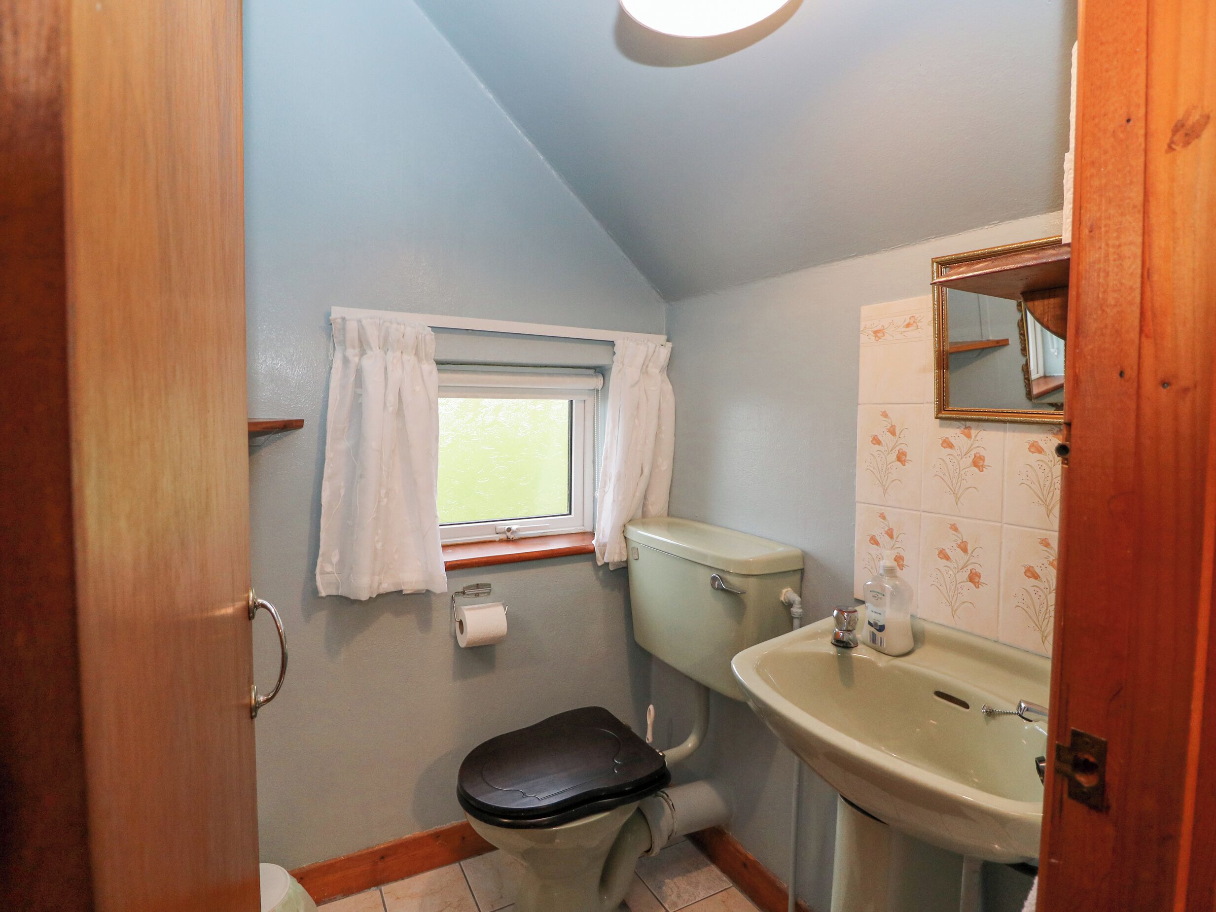 Ein kleines Badezimmer mit Toilette, Waschbecken und Fenster.
