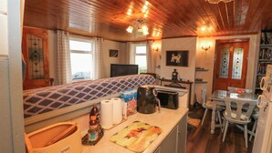 A cozy kitchen with wooden cabinets, a breakfast bar, and a dining area with a table and chairs. - Lehanmore House (Garinish)