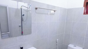 A bathroom with a sink, toilet, and a shower with a handheld showerhead. - Tropical Suites (Negombo)