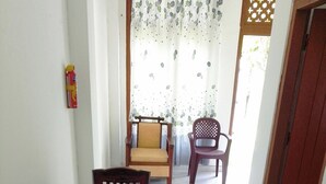 A dining area with a round table, two wooden chairs, a cushioned chair, and a plastic chair. - Tropical Suites (Negombo)