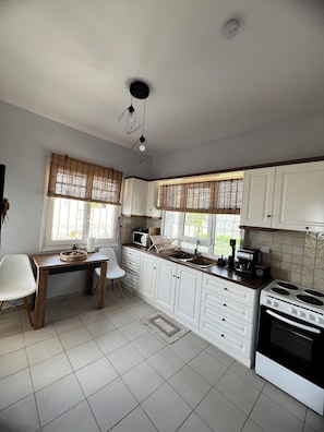 A kitchen with white cabinets, a wooden table, and a stove.