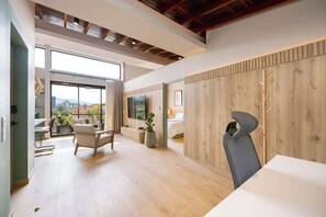 Ein modernes Hotelzimmer mit großem Fenster, Essbereich und einer Wand mit Holzpaneelen.