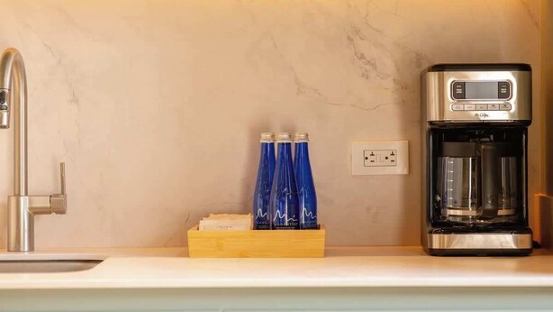 A kitchen with a modern coffee maker, a faucet, and a wooden box with blue bottles. - Digital Nomad Paradise 1BR Luxury & Peace with A/C (Medellín)