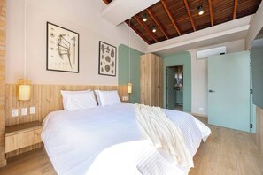 Ein geräumiges Schlafzimmer mit einem großen Bett, einem Holz-Kopfteil und zwei Wandleuchten.