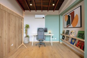 Ein moderner Arbeitsraum mit Holzboden, einem Schreibtisch mit Stuhl, einem Blumentopf und einem Bücherregal mit Büchern und Plattenspieler.