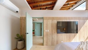 A modern bedroom with a sloped ceiling, a large window, and a wooden wall panel. - Digital Nomad Paradise 1BR Luxury & Peace with A/C (Medellín)