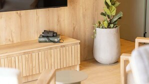 Un salon moderne avec un banc en bois, une plante en pot et un téléviseur à écran plat fixé au mur.