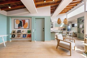 Une pièce spacieuse avec un plafond en bois, une bibliothèque remplie de livres et de disques, et un grand tableau abstrait.