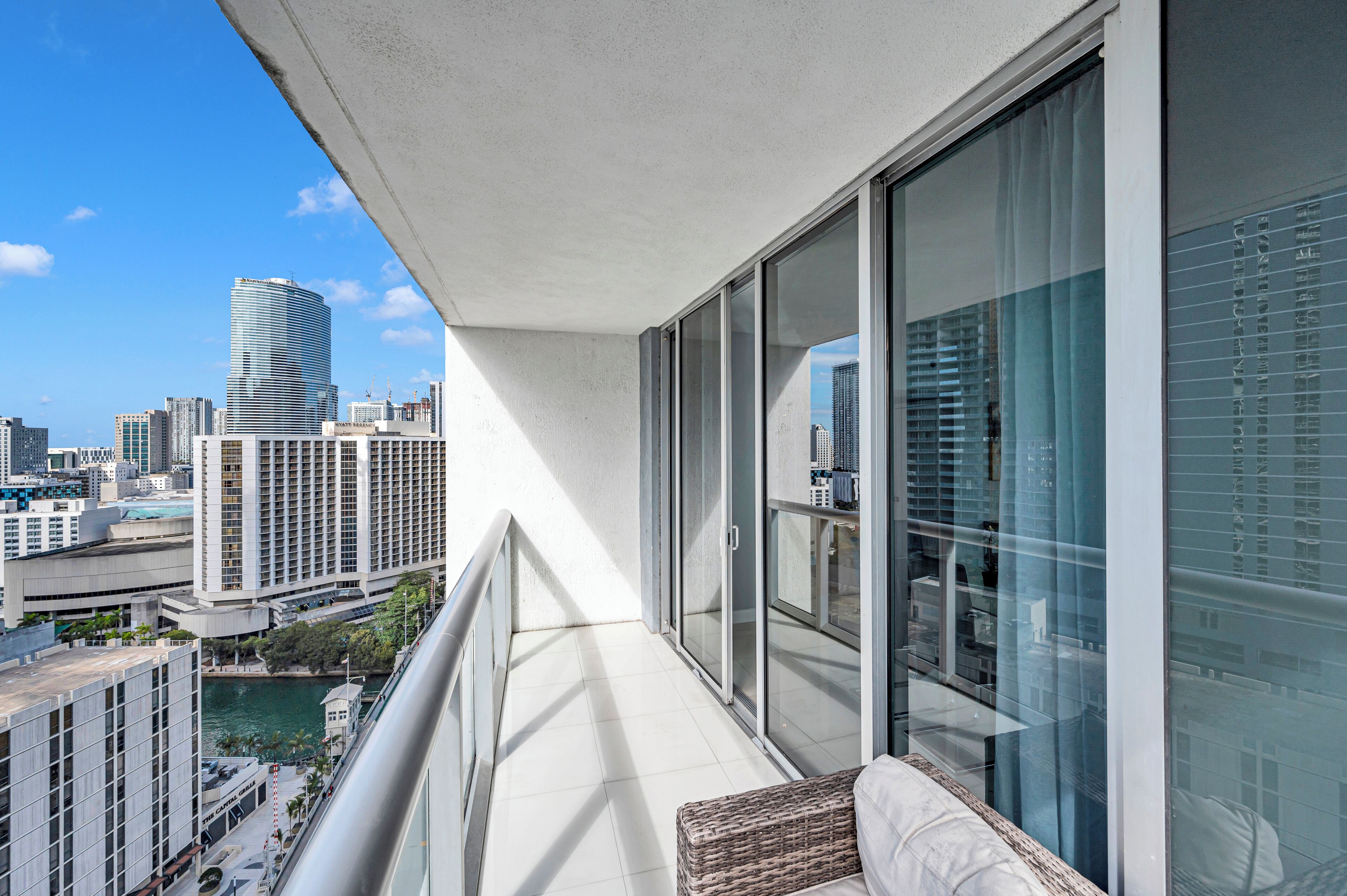 A balcony with a view of a cityscape, including high-rise buildings and a body of water.