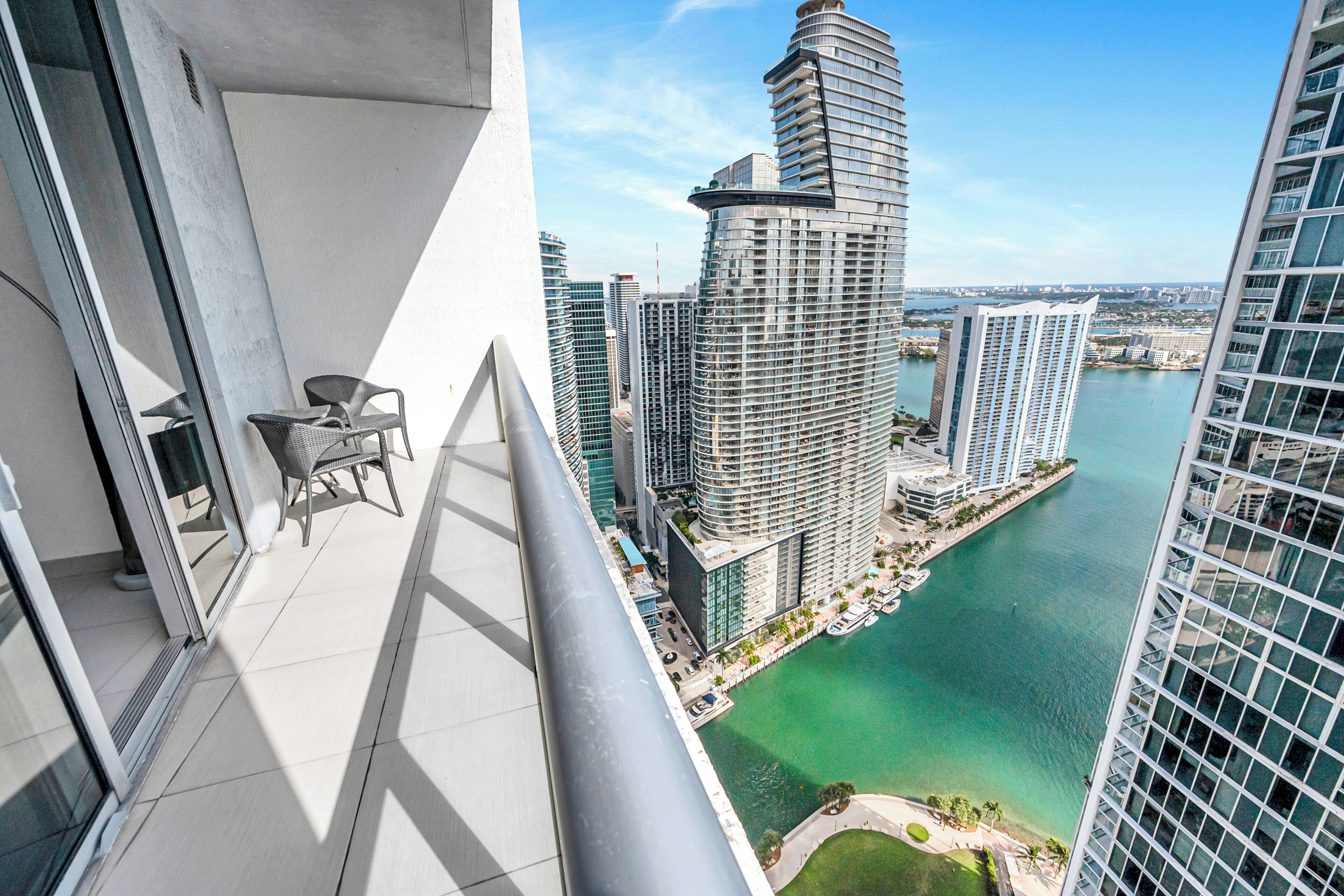 A high-rise building with a view of a body of water and other buildings.
