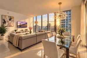 A modern living room with a sofa, a glass dining table, and a large window with a city view. - Icon Brickell  (Miami)