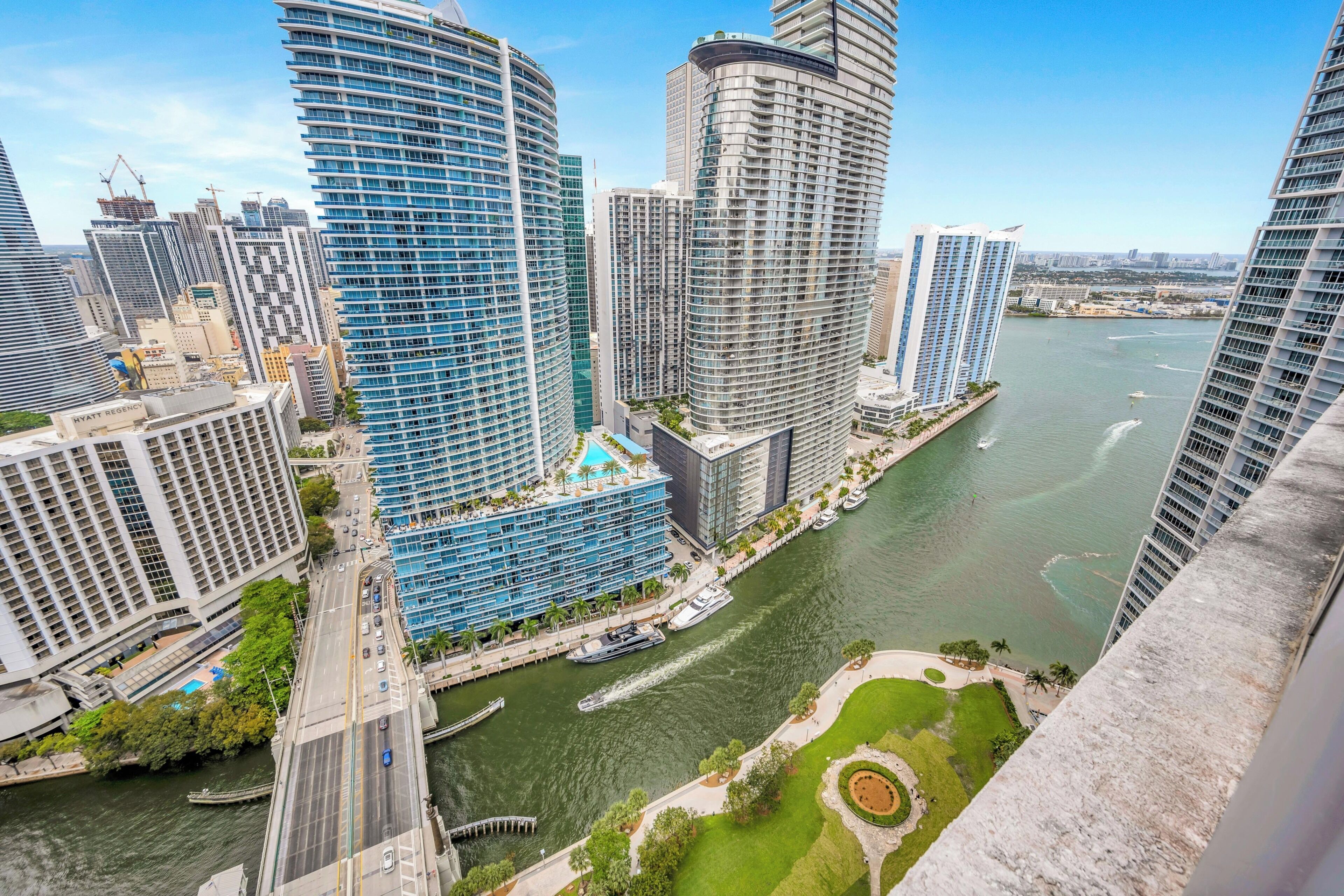 A high-rise hotel with a waterfront view, a curved glass facade, and a rooftop pool.