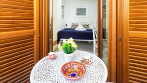 Een kamer met een bed, een tafel met een decoratieve schaal en bloemen, en een witte stoel.