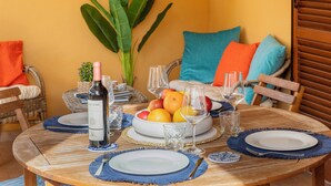 Een ronde houten eettafel gedekt met borden, bestek en een fles wijn.
