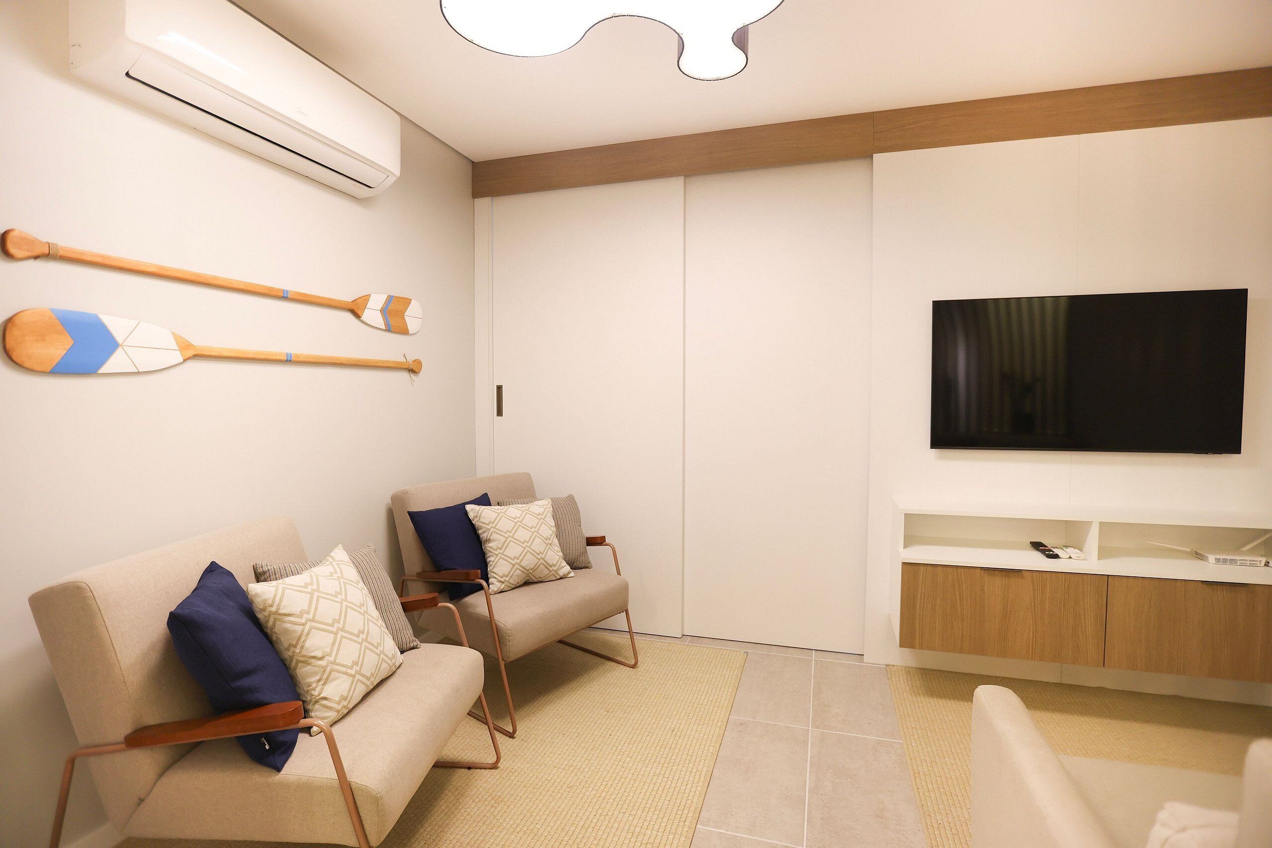 A modern living room with two sofas, a flat-screen TV, and a wooden cabinet.