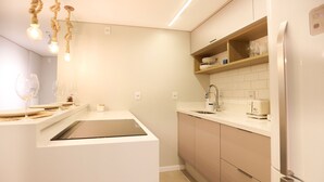 Una cocina moderna con una isla integrada, armarios blancos, un refrigerador de acero inoxidable e iluminación colgante.