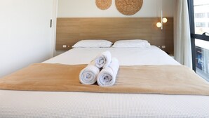 Una habitación de hotel con una cama, dos adornos tejidos en la pared y un equipo de aire acondicionado.