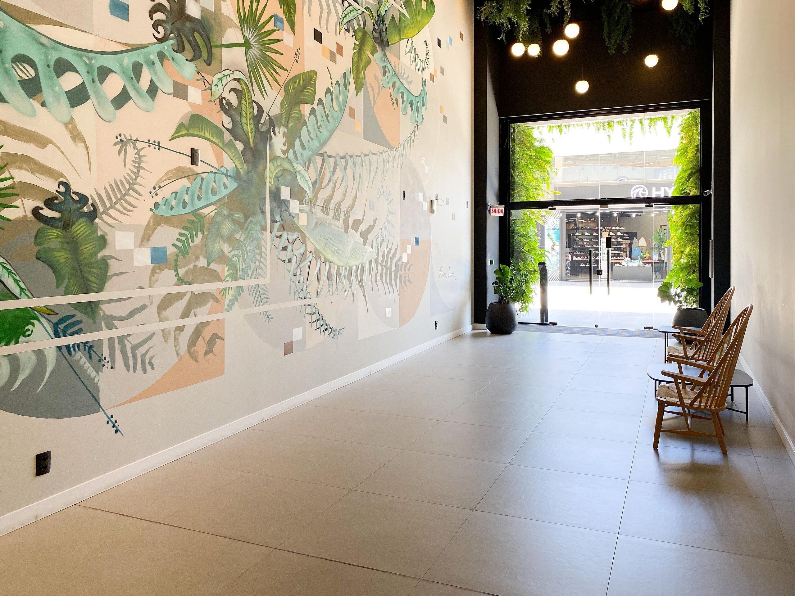 Un interior moderno con un gran mural, una zona de recepción y vistas al exterior.