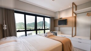 Een moderne hotelkamer met een groot bed, een aan de muur bevestigde televisie en uitzicht op de bergen.