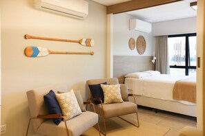 A hotel room with two armchairs, a bed, and a view of the outside. - Studio Shopping OKA Floripa - SOK108 (Florianopolis)