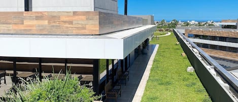 Un edificio moderno con techo plano, zona de estar al aire libre y vistas a la ciudad.