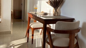 Ein Essbereich mit einem Holztisch und Stühlen, einer Vase mit Trockenpflanzen und einem Glas Orangensaft.