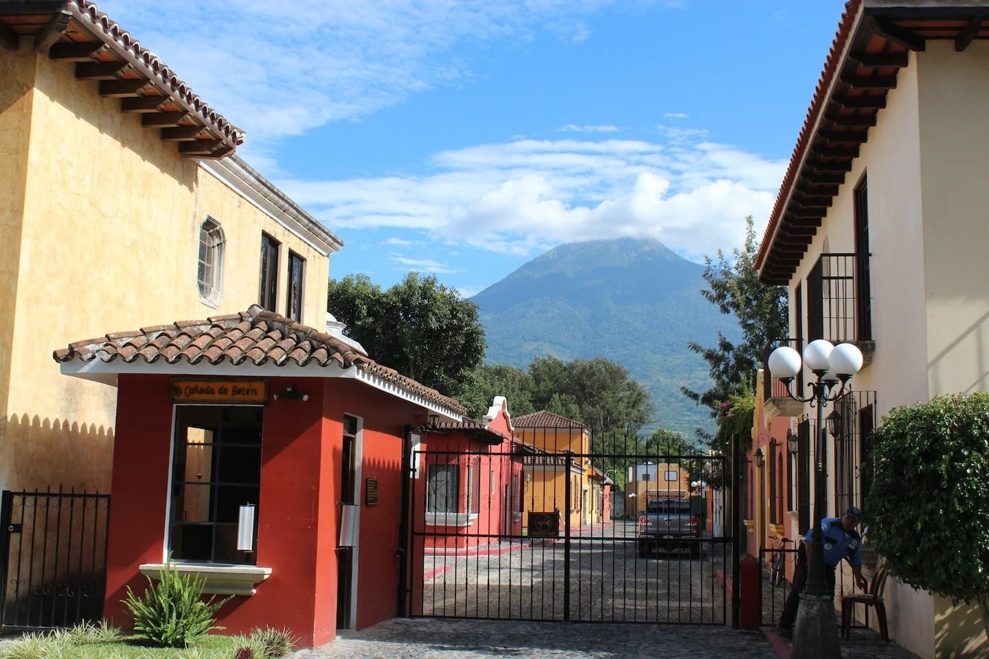 A street with buildings, a gate, and a mountain in the background.
