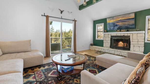 A living room with a fireplace, a glass coffee table, and a sofa.