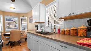 A kitchen with white cabinets, a countertop, and a dining area with chairs.