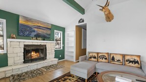 A living room with a fireplace, a sofa, a coffee table, and a mounted animal head.