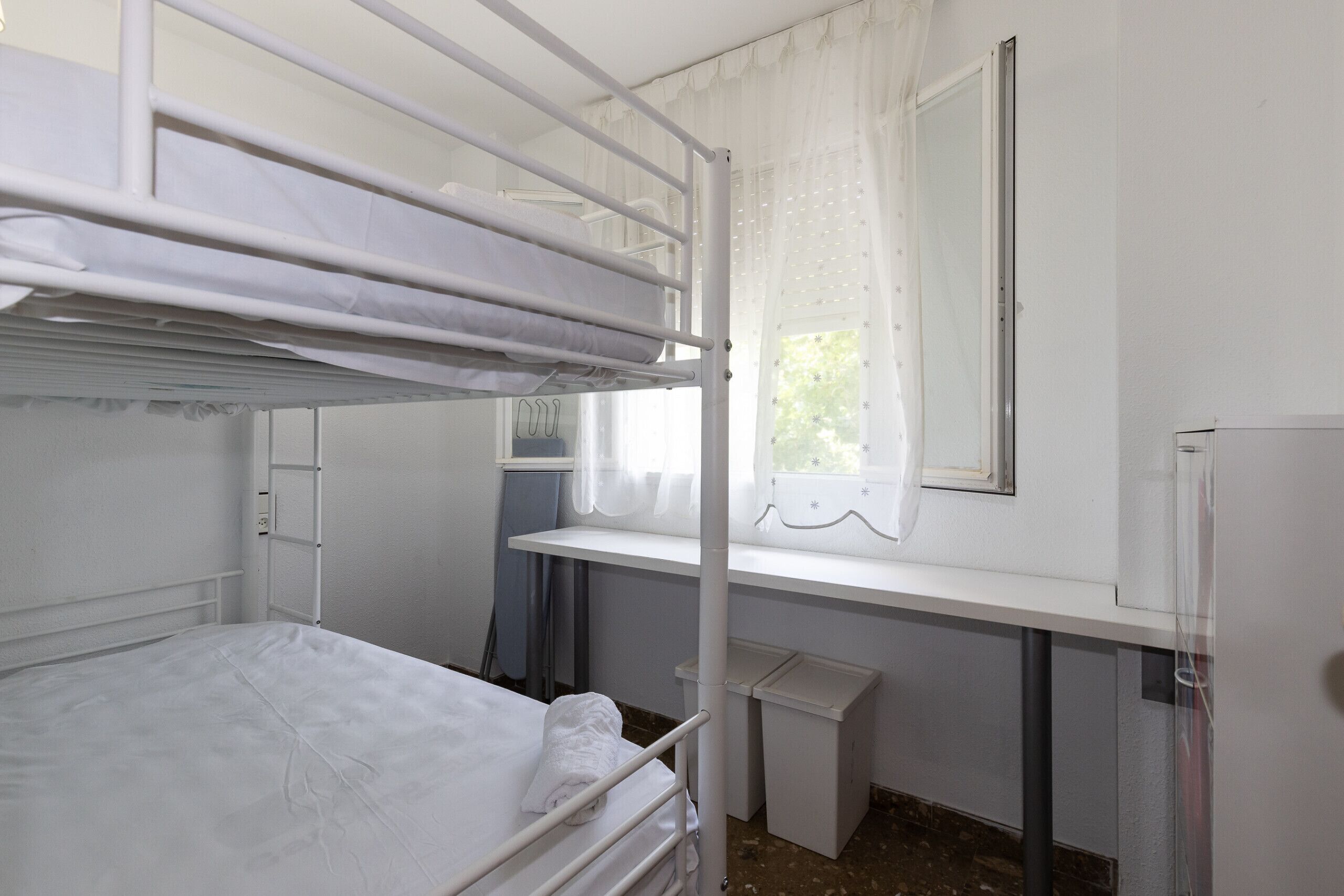Ein Schlafzimmer mit Etagenbett, Schreibtisch und Fenster.