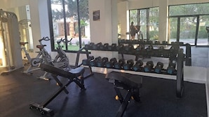 A gym with exercise equipment, dumbbells, and large windows.