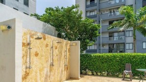 An outdoor shower area with a stone wall, a chair, and a table.