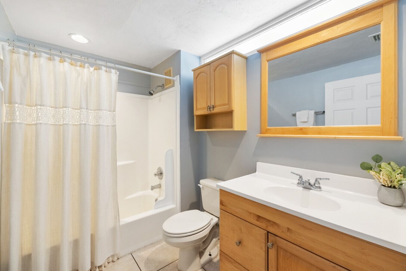 A bathroom with a bathtub, toilet, and vanity with a mirror.