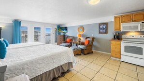 A hotel room with a bed, a chair, a table, a microwave, and an oven.