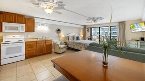 A compact living space with a kitchenette, a dining area, a bed, and a balcony with a TV. - Balcony 🌴 King Bed + Sofa Bed 🌴 Water Views (Cedar Key)