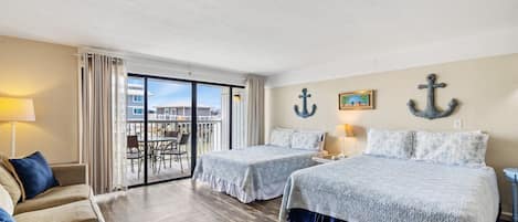 Habitación de hotel con dos camas, un balcón con vistas y decoración náutica.