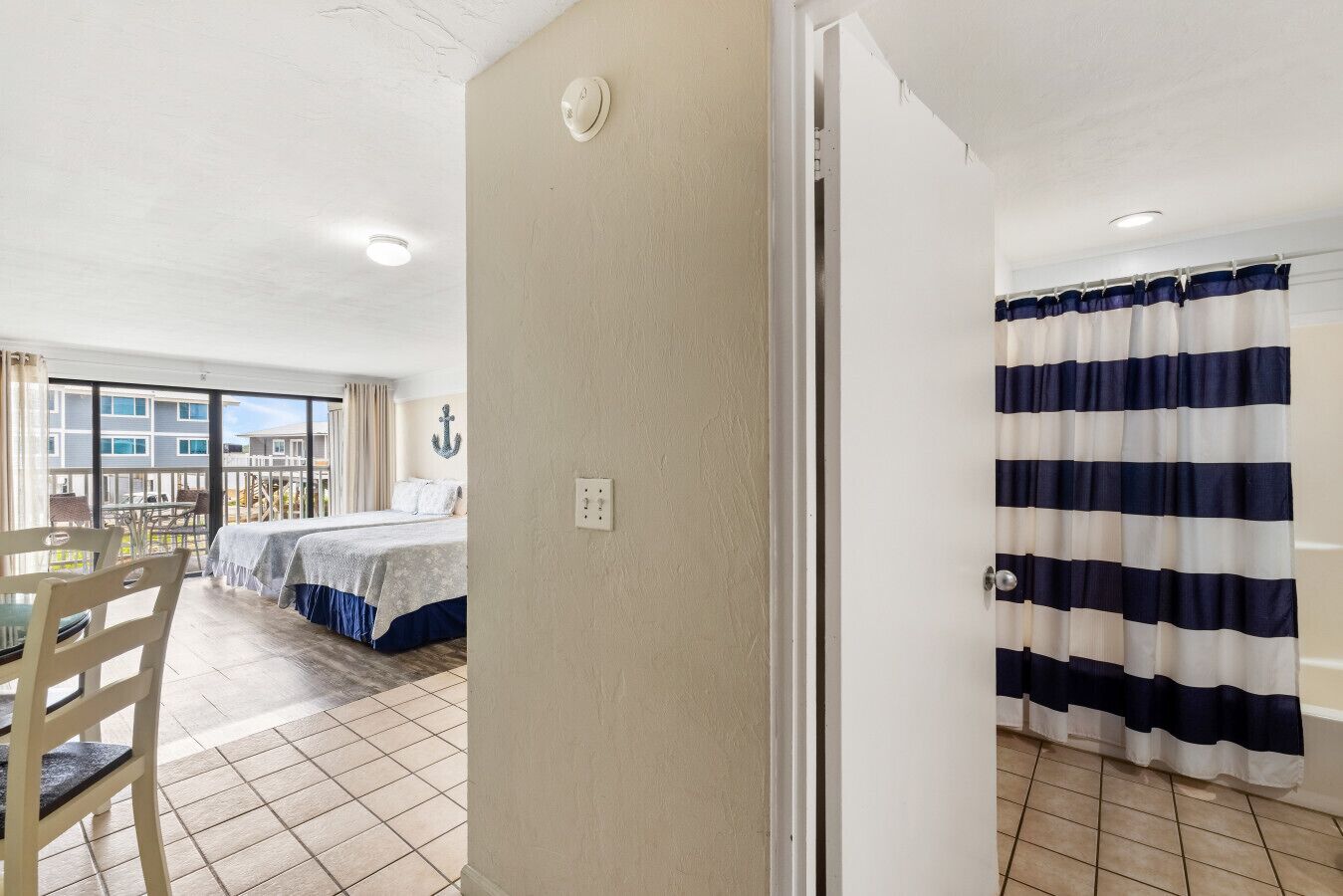A hotel room with a bed, a dining table, and a view of the outside.