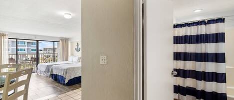 A hotel room with a bed, a dining table, and a view of the outside.
