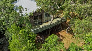 A wooden house with a deck, surrounded by dense trees. - A Cozy Canopy Getaway in Cedar Key (Cedar Key)