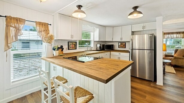A modern kitchen with white cabinetry, a wooden island, stainless steel appliances, and pendant lighting.