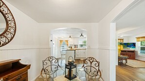 A dining area with a glass table, metal chairs, and a decorative mirror.